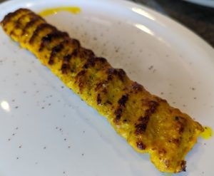 A chicken skewer that's vibrantly yellow from its turmeric seasoning - Salang Kabob House