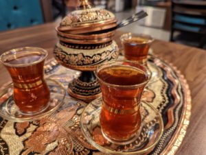 Turkish tea in small, translucent glasses with gold-coloured bands around the cinched middles, on top of a lovely hammered-copper platter - Pita Bell Kabab
