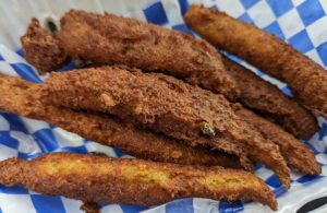 Akra from Margo Xpress - the deep fried salt cod fritters are finger-like in shape, with crisp, brown, latticed-edges. Several sit in a blue-checkered-paper-lined takeout container.